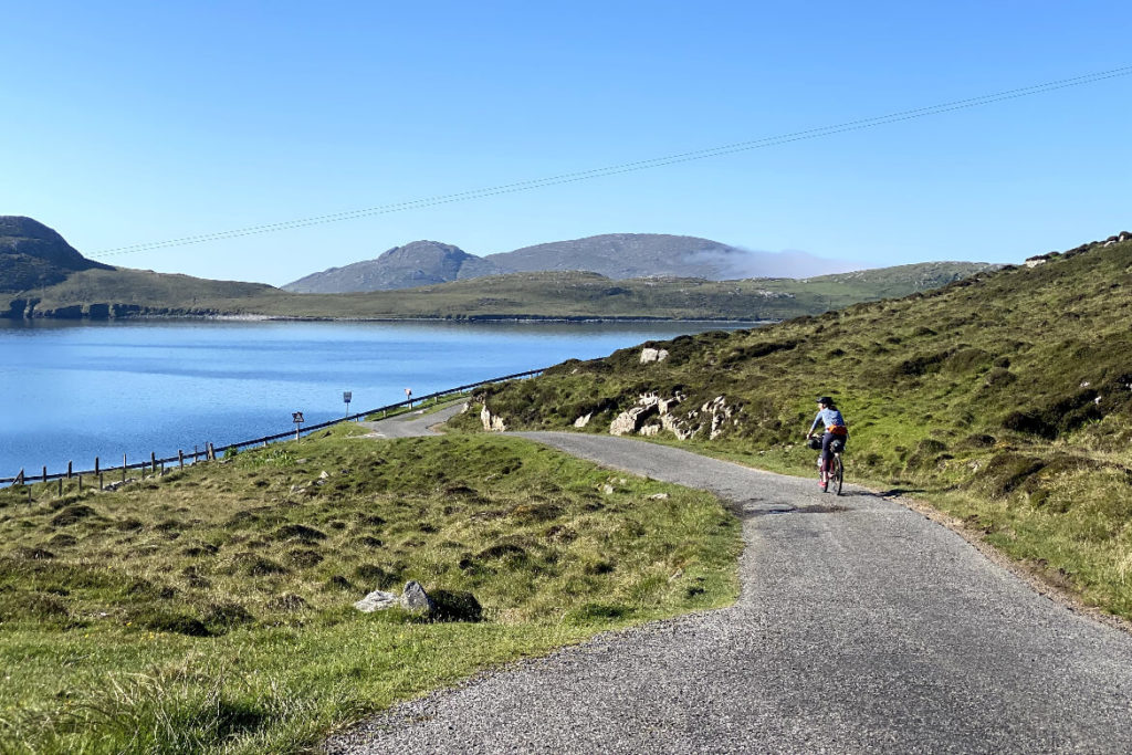 woman cycling on the road looking out to sea on Vatersay