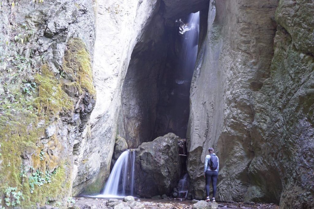 woman standing looking up at a waterfall